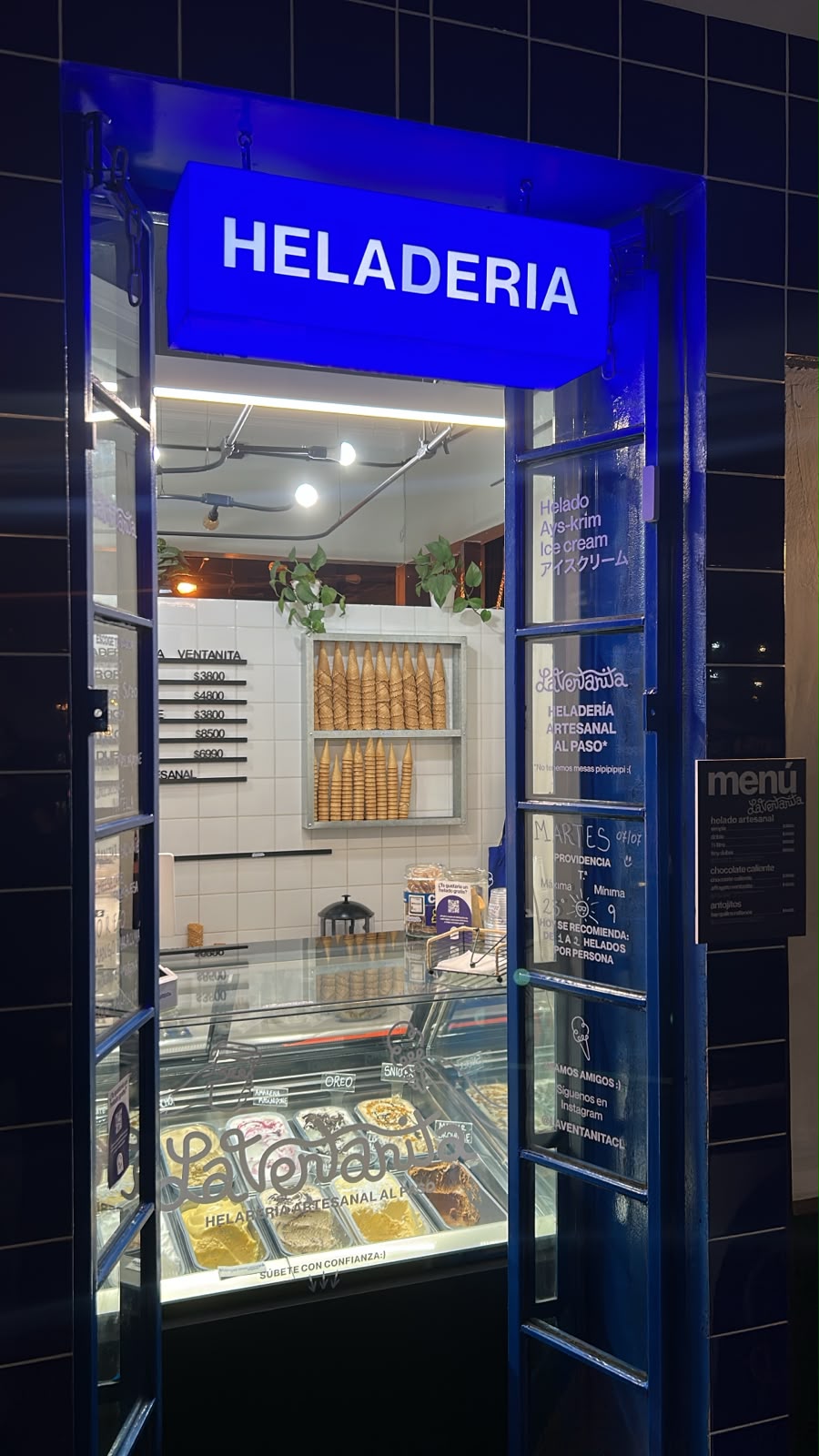 Fachada de La Ventanita de noche, con el letrero Heladería iluminado en azul